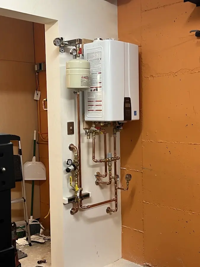 Plumbing technician inspecting water heater connections in LaFayette
